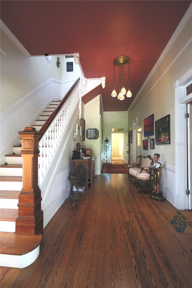 entrance foyer with an inviting chandelier, dark wood-type flooring, and crown molding