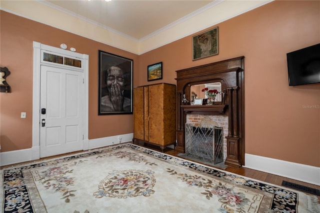 entryway featuring ornamental molding, a brick fireplace, and hardwood / wood-style flooring