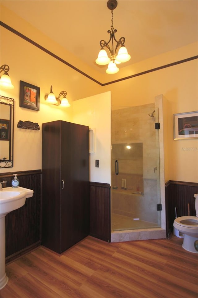 bathroom featuring wood walls, walk in shower, wood-type flooring, an inviting chandelier, and toilet