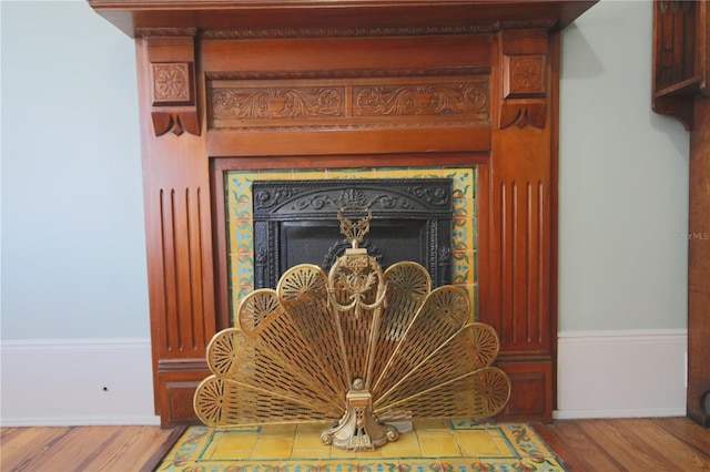 details featuring a tiled fireplace and hardwood / wood-style flooring