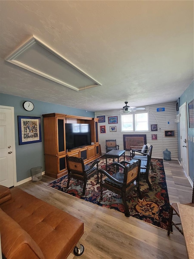 living room with ceiling fan, hardwood / wood-style flooring, and a textured ceiling