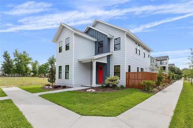 contemporary home featuring fence, board and batten siding, and a front yard