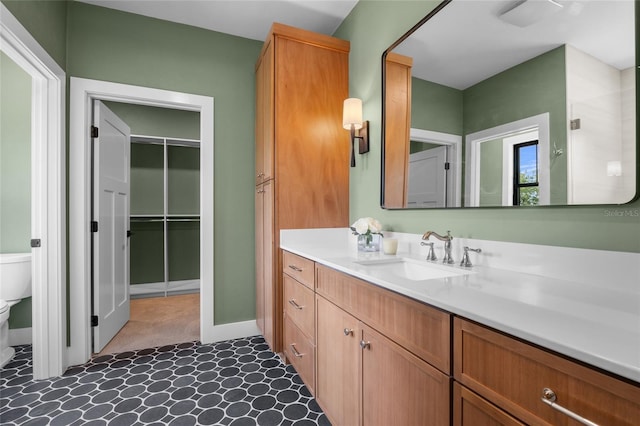 bathroom featuring tile patterned floors, a spacious closet, vanity, baseboards, and toilet