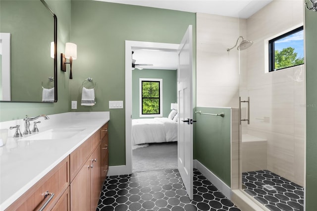 ensuite bathroom featuring a tile shower, a wealth of natural light, baseboards, and ceiling fan