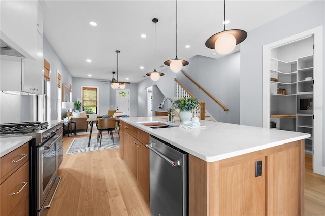 kitchen featuring light wood-style flooring, appliances with stainless steel finishes, a ceiling fan, and a sink