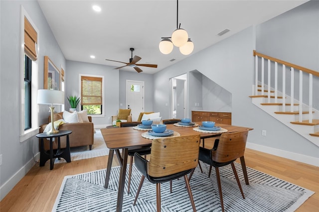 dining space with baseboards, light wood-style flooring, visible vents, and stairs