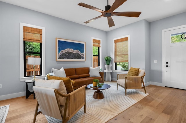 living room featuring baseboards, a ceiling fan, visible vents, and light wood-type flooring