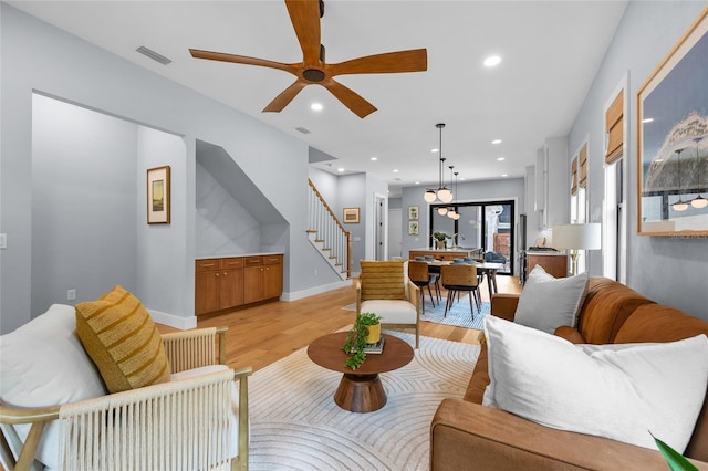 living room with light wood finished floors, visible vents, recessed lighting, stairs, and ceiling fan