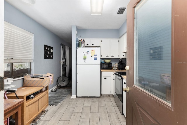 kitchen with white cabinets, light hardwood / wood-style flooring, white fridge, and stainless steel electric stove