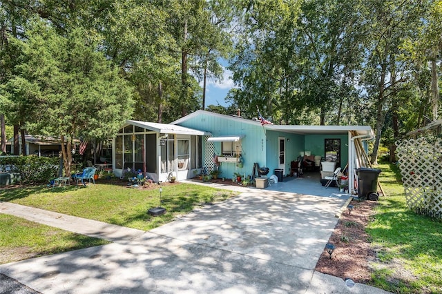 view of front of home with a front yard, a sunroom, and a carport