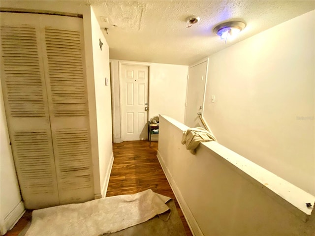 hallway featuring a textured ceiling and dark hardwood / wood-style floors