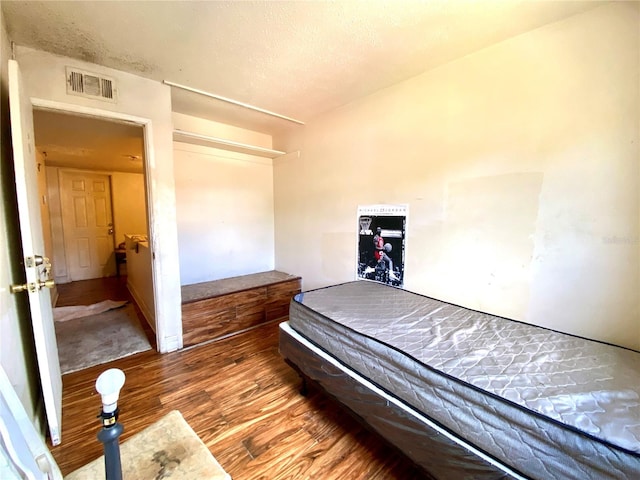 bedroom with a textured ceiling and hardwood / wood-style flooring