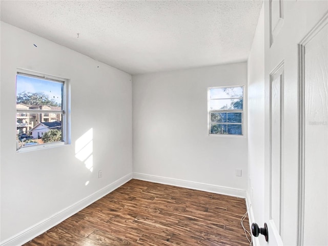 unfurnished bedroom with multiple windows, dark hardwood / wood-style flooring, and a textured ceiling