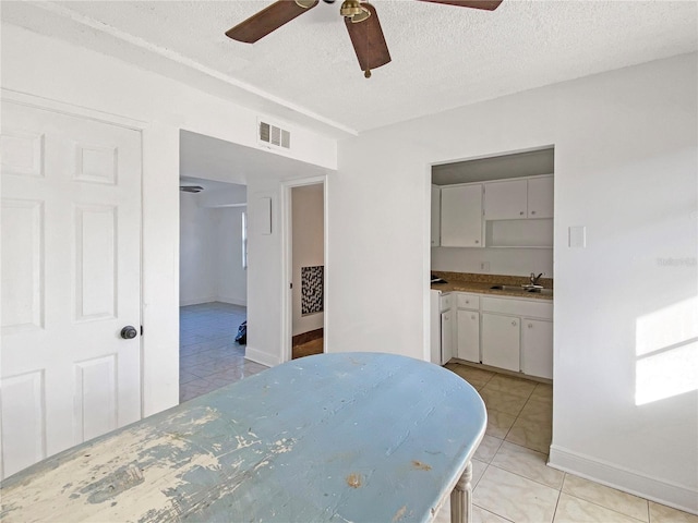 tiled dining area featuring ensuite bathroom, sink, ceiling fan, and a textured ceiling