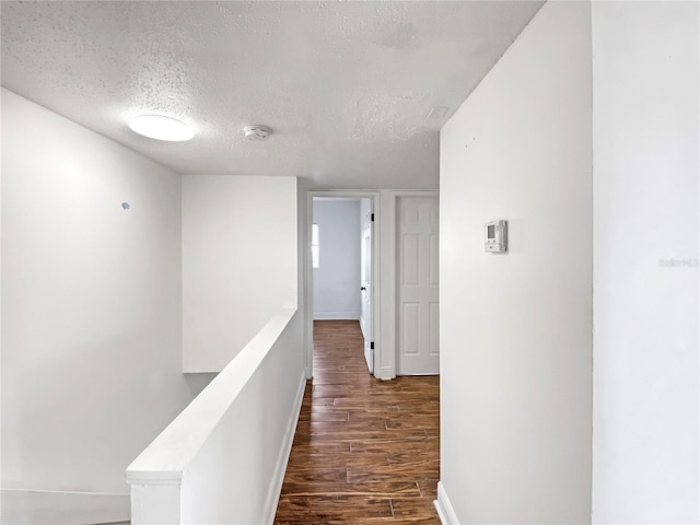 corridor with dark hardwood / wood-style floors and a textured ceiling