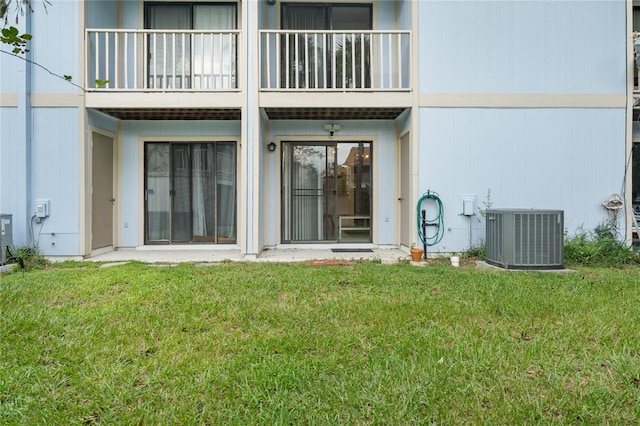 back of house with cooling unit, a balcony, and a lawn