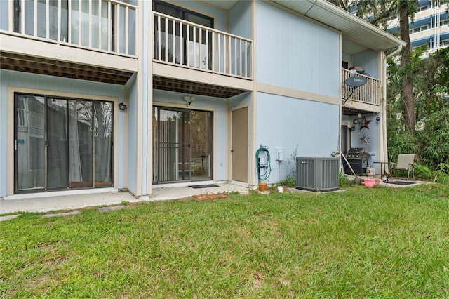 back of property with a lawn, a balcony, and central air condition unit