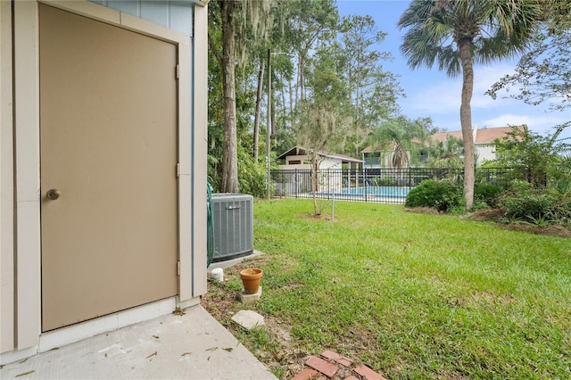 view of yard featuring a fenced in pool and central AC