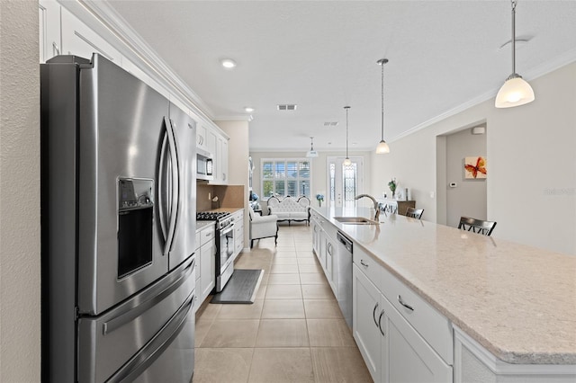 kitchen with appliances with stainless steel finishes, hanging light fixtures, and white cabinetry