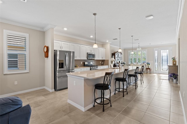 kitchen featuring a breakfast bar area, decorative light fixtures, a large island with sink, stainless steel appliances, and white cabinetry