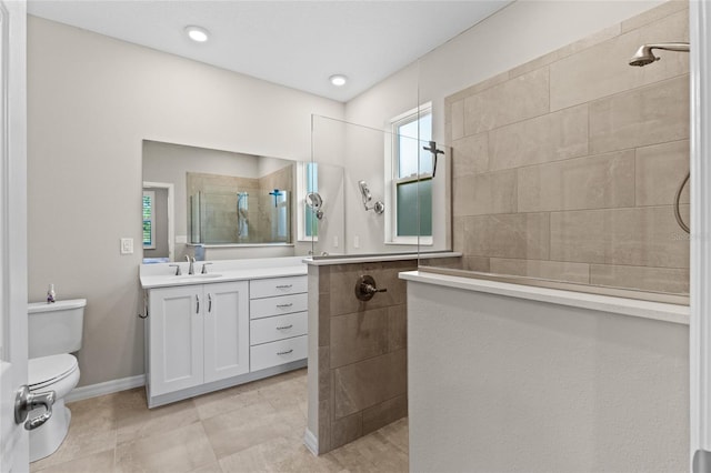 bathroom featuring plenty of natural light, a tile shower, vanity, and toilet