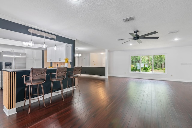 kitchen featuring ceiling fan with notable chandelier, hanging light fixtures, dark wood-type flooring, and stainless steel fridge with ice dispenser