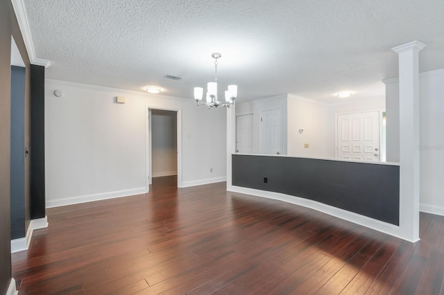 spare room featuring ornamental molding, a chandelier, a textured ceiling, and dark hardwood / wood-style floors