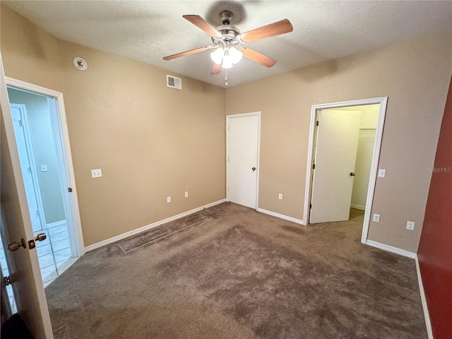 unfurnished bedroom with carpet flooring, baseboards, visible vents, a closet, and a walk in closet