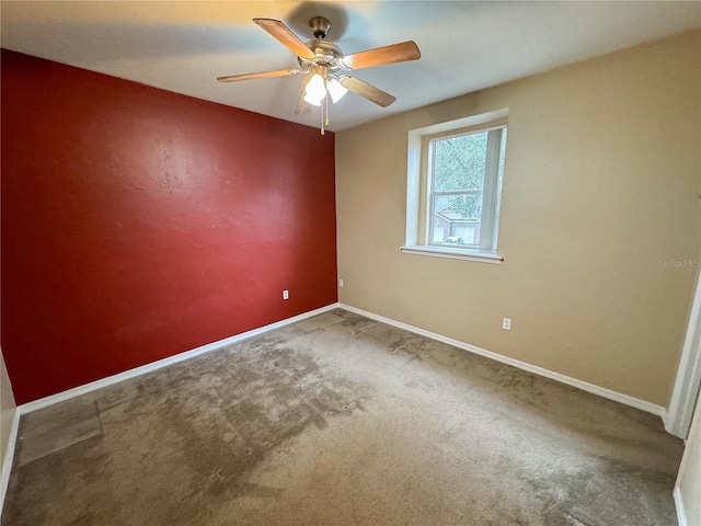 carpeted empty room featuring baseboards and ceiling fan