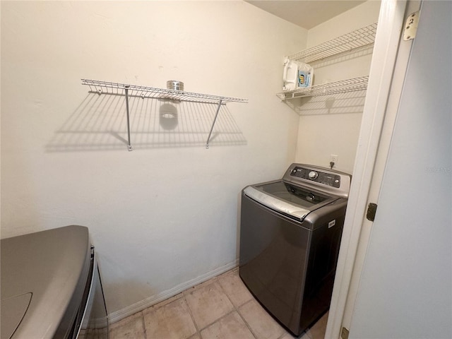 washroom featuring separate washer and dryer, baseboards, laundry area, and light tile patterned floors