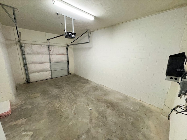 garage with concrete block wall and a garage door opener