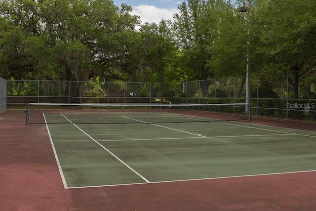view of tennis court with community basketball court and fence