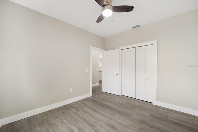 unfurnished bedroom with a closet, light hardwood / wood-style floors, and ceiling fan