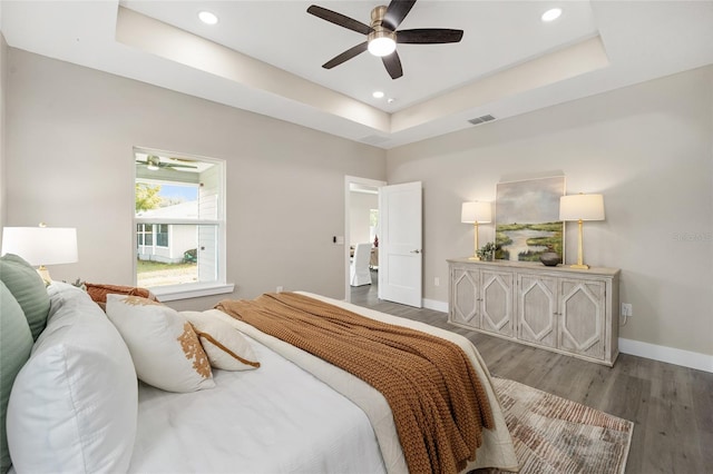 bedroom with a tray ceiling, ceiling fan, and hardwood / wood-style flooring