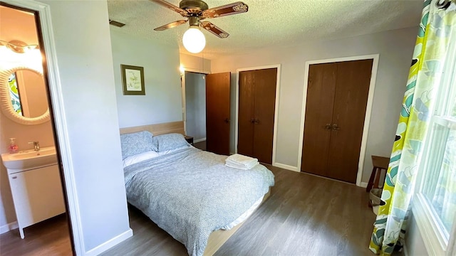 bedroom with a textured ceiling, ceiling fan, sink, and dark hardwood / wood-style flooring