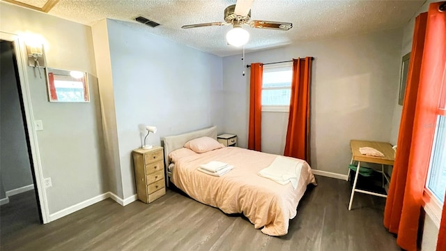 bedroom with ceiling fan, dark hardwood / wood-style floors, and a textured ceiling