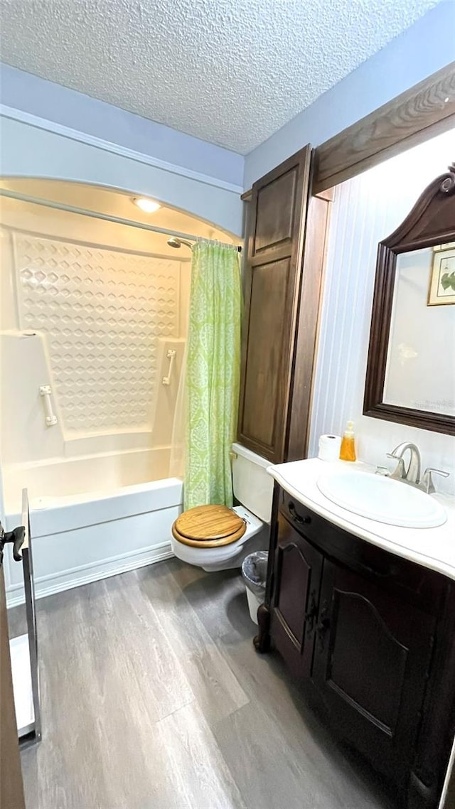 full bathroom featuring vanity, wood-type flooring, a textured ceiling, shower / bathtub combination with curtain, and toilet