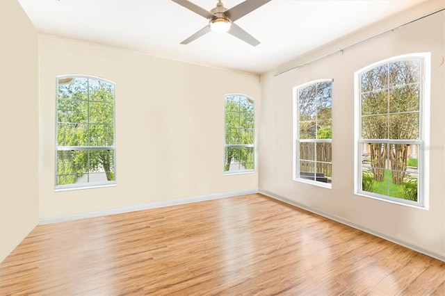 spare room with light wood finished floors, ceiling fan, baseboards, and a wealth of natural light