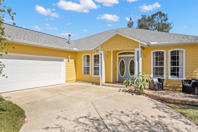 ranch-style home with covered porch, concrete driveway, a shingled roof, and an attached garage