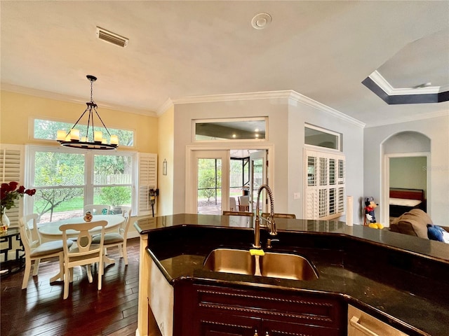 kitchen with dark wood-type flooring, sink, an inviting chandelier, ornamental molding, and decorative light fixtures