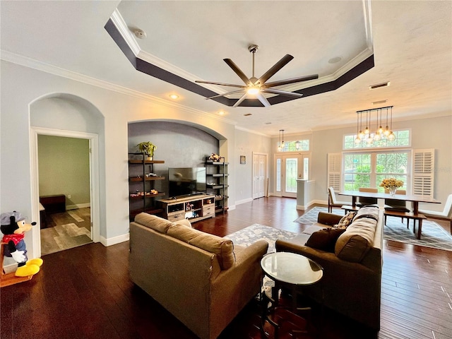 living room with crown molding, a tray ceiling, and dark hardwood / wood-style floors