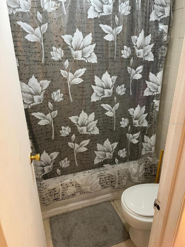 bathroom with a shower with curtain, toilet, and tile patterned floors