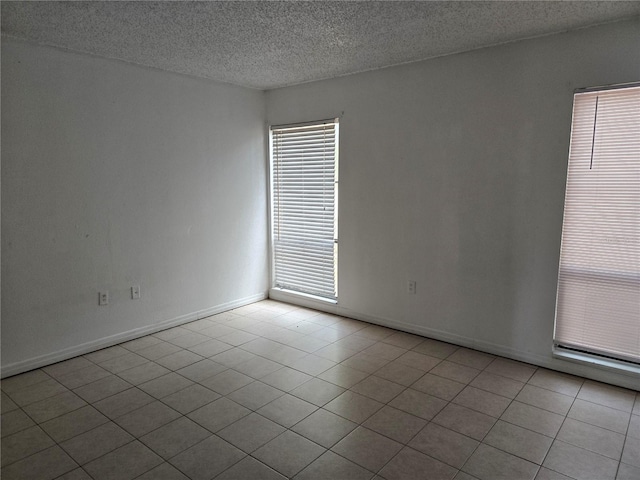2811 SW Archer Rd Unit R-143, Gainesville, FL 32608 - spare room featuring a textured ceiling, tile patterned floors, plenty of natural light, and baseboards