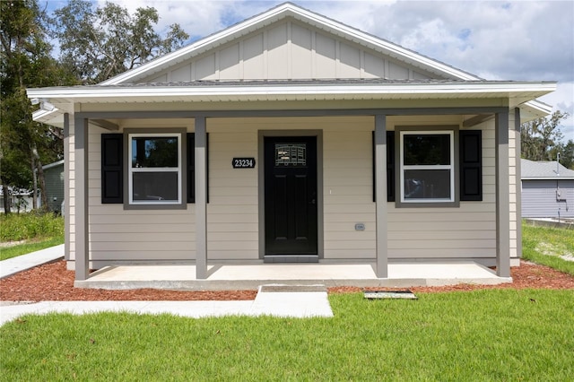 bungalow with board and batten siding, a front yard, and covered porch