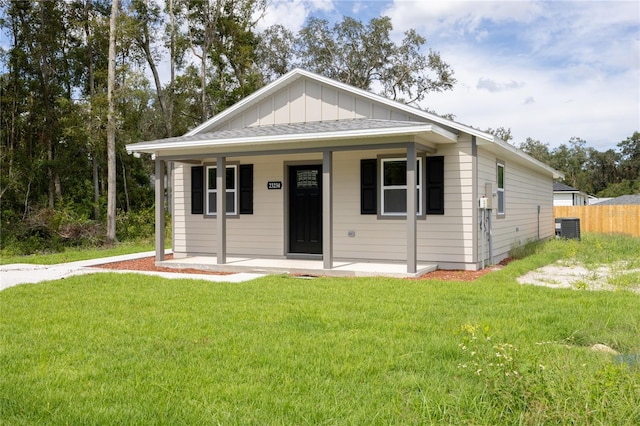 bungalow-style home featuring cooling unit, a front lawn, and a porch