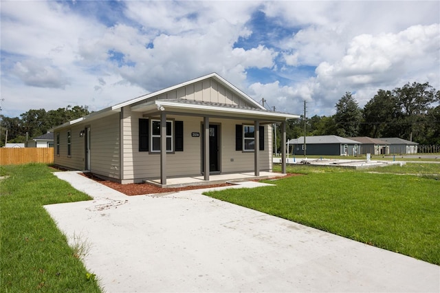 view of front of home with fence, a porch, board and batten siding, and a front yard