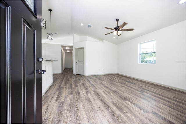 spare room featuring wood finished floors, ceiling fan, baseboards, lofted ceiling, and visible vents