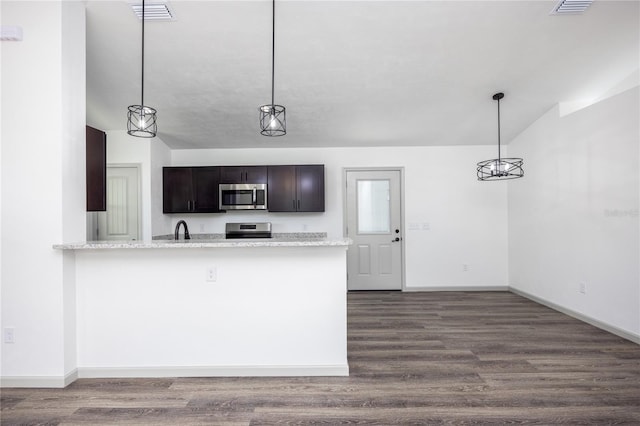 kitchen with dark brown cabinets, kitchen peninsula, stainless steel appliances, pendant lighting, and dark hardwood / wood-style floors