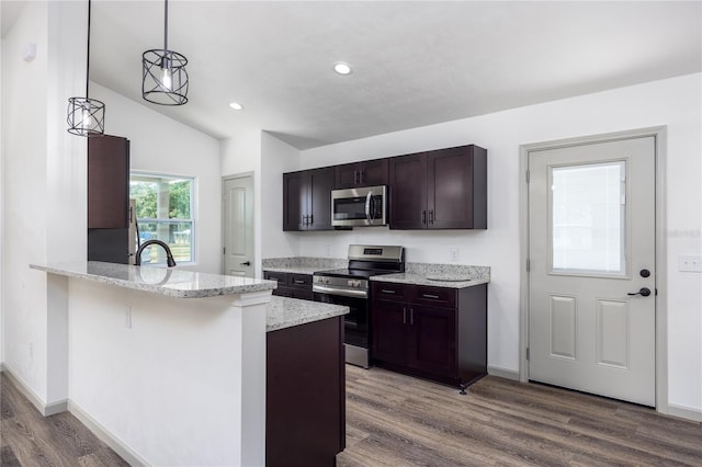 kitchen with dark brown cabinets, wood finished floors, stainless steel appliances, light stone countertops, and recessed lighting