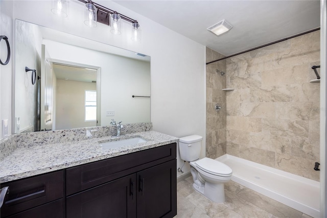 bathroom with vanity, toilet, and tiled shower